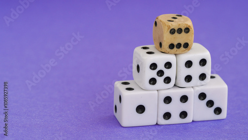 Stacked dice with a weathered vintage die on top, symbolizing decision-making, chance, and contrasts between the old and new. Purple background enhances creativity and playfulness.