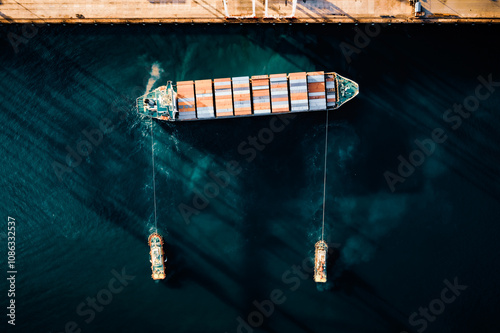 Top view of a large cargo ship loading and unloading containers at a deep sea port. Aerial view of international shipping and logistics hu