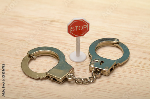 The juxtaposition of the "STOP" sign and the handcuffs creates a visual representation of the limitations and restrictions imposed by legal systems