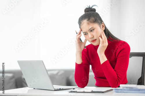 A businesswoman sits at her desk, stressed and anxious while looking at her laptop. She talks online, analyzes tasks, and struggles to plan effectively, battling pessimism and work pressure.