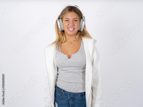 Portrait of dissatisfied Beautiful teen girl wearing white jacket smirks face, purses lips and looks with annoyance at camera, discontent hearing something unpleasant