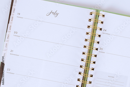 Planner opened to month of July shows empty weekly sections, providing space for scheduling events, jotting down notes, organizing tasks.