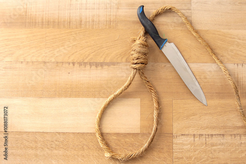 Top View of Knife and Suicide Rope Over Wooden Background