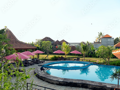 Luxurious outdoor pool and patio area with umbrellas and chairs in front of a beautiful house