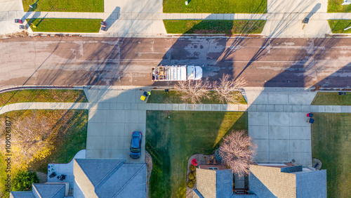 Aerial view above a garbage truck in a residential suburban area in fall morning