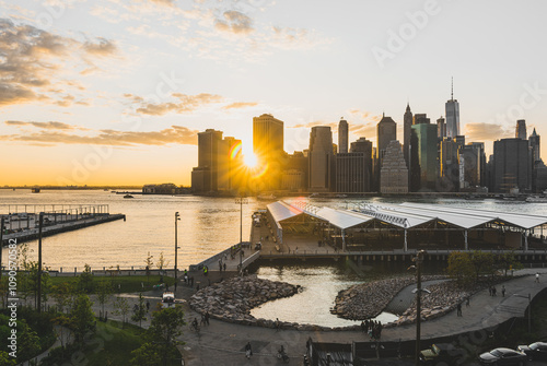 A sunset photo lower Manhattan, financial district with a sunburst over Brooklyn bridge park, shot from Dumbo Brooklyn.