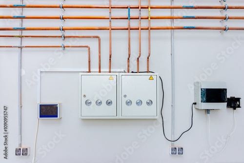 Industrial Copper Piping System with Electrical Panel and Gauges: Clean, modern industrial setting featuring copper pipes, electrical panel, pressure gauges, and electrical components.