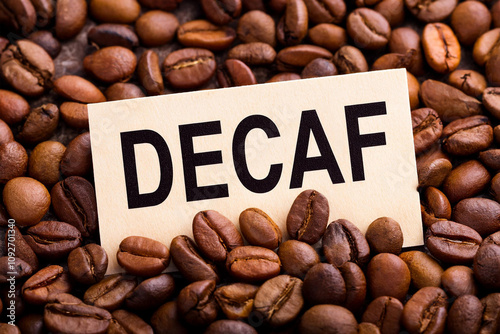 Decaf word on roasted coffee beans background. Concept of decaffeinated coffee and low caffeine coffee.