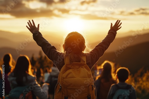 A group of joyful hikers with backpacks raise their arms in celebration while watching the sun rise majestically over distant mountains, basking in golden light.