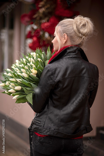 Blonde girl in a leather jacket with a large bouquet of tulips