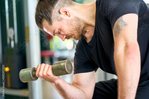 Close up a caucasian man in black shirt try to hard workout with grumbell for weight training in sport gym.