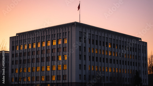 A Soviet brutalist building at dawn with glowing illuminated windows