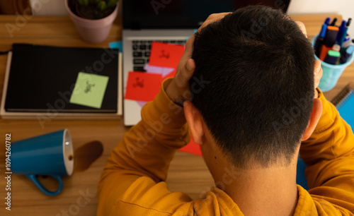 Close up of young man with hands on head on desk because of having too much work, overwork concept