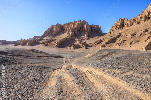 Desert road and Yardang landform mountain natural landscape under blue sky. Road trip in no man's land.