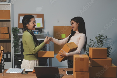 Startup SME small business entrepreneur of freelance Asian woman wearing apron using laptop and box to receive and review orders online to prepare to pack sell to customers, online sme business ideas.