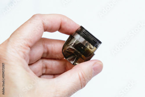 Replacement cartridge for electronic cigarette in a person's hand. A device for nicotine liquid. POD-system for smoking.