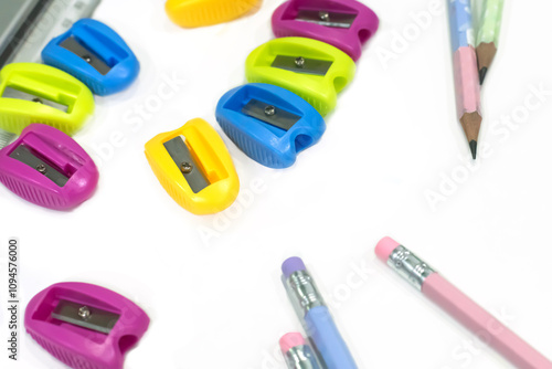 Multi-colored pencil sharpeners and multi-colored pencils on a white table