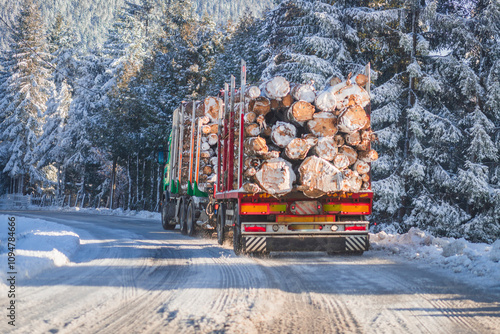 A loaded timber truck transporting snow-covered logs through a snowy forest. The winter road is surrounded by frosted pine trees, creating a serene and cold atmosphere.