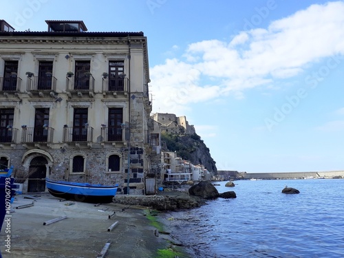 Un angolo caratteristico di Chianalea di Scilla, un palazzo sul mare e le barche blu.