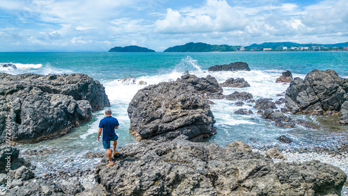 Tourist man contemplating the turquoise sea on a sunny day at the Jaco viewpoint in Puntarenas, Costa Rica