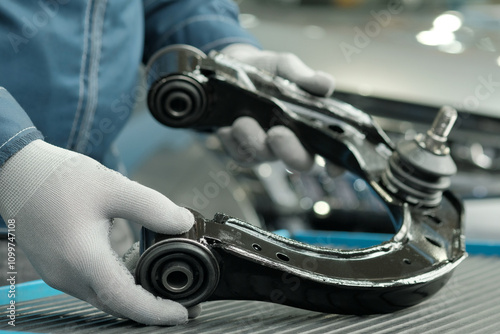 Repair of the car suspension. A new front suspension lever is in the hands of an auto mechanic. External inspection and inspection of the spare part before installation.