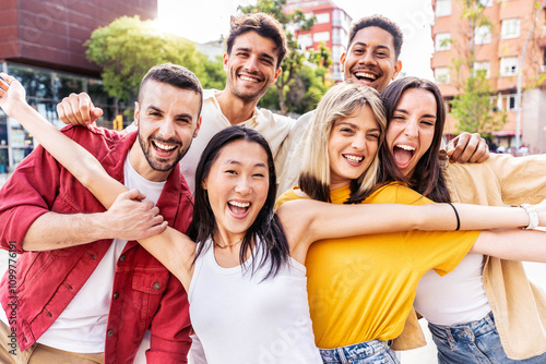 Multiracial young people smiling at camera outside - Happy group of friends having fun hanging out in city street