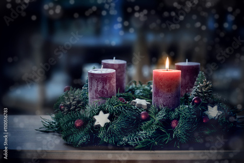 Advent wreath with the first lit candle and Christmas decoration outdoors in a patio at night in bluish light, snowy bokeh, copy space, colorized photo, selected focus