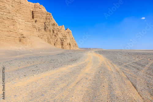 Desert sand road and Yardang landform mountain natural landscape in Xinjiang, China. Road trip in no man's land. Outdoor natural background.