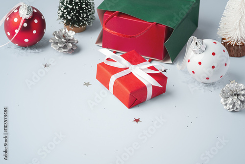 Christmas gift box with green paper bag and christmas decor on gray table background