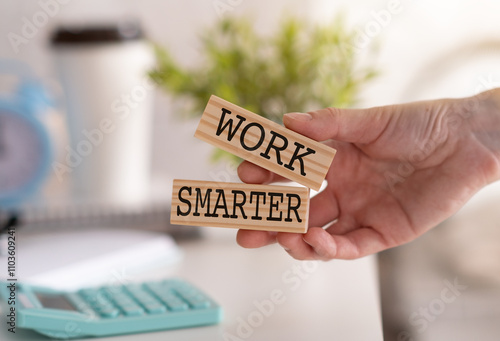 Work Smarter word written on wooden block in hand, clipboard and calculator