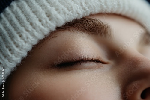 A serene close-up of a peaceful closed eye under the cozy protection of a knit hat, symbolizing restful tranquility and the softness of quiet moments.