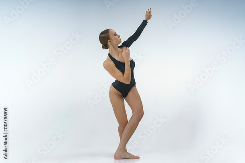 young female dancer in a bodysuit and barefoot shows elements of modern choreography with an eversion of the arms