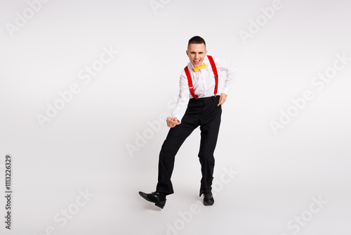 Energetic young man performing dance moves in stylish outfit with white background