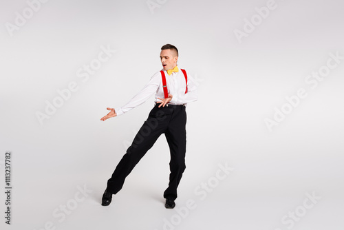 Young man in vintage fashion performing an energetic dance, displaying charisma and elegance against a white background