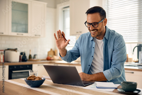 Happy entrepreneur greeting someone during video call while working at home.