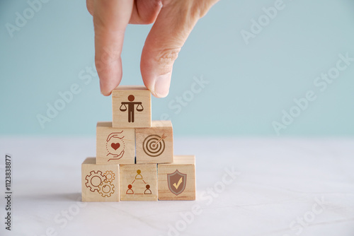 Hand holding wooden block with Ethical icons, business ethics and corporate compliance concept