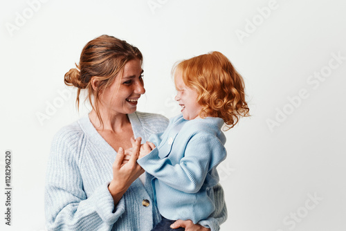 Happy mother holding smiling little girl in arms in front of white background for family, love, and bonding concept